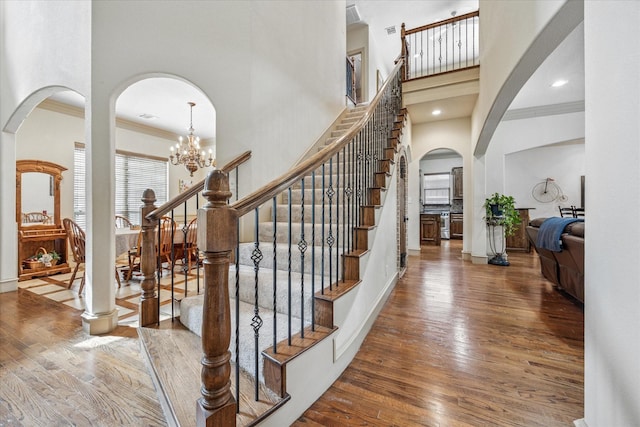 entrance foyer featuring arched walkways, crown molding, recessed lighting, wood-type flooring, and a high ceiling