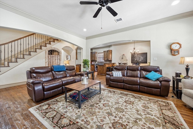 living room with arched walkways, crown molding, visible vents, stairway, and wood finished floors