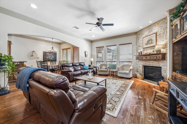 living area featuring visible vents, wood-type flooring, ornamental molding, a fireplace, and ceiling fan with notable chandelier