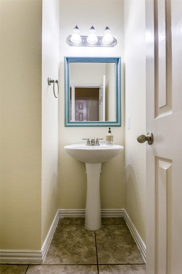 bathroom featuring tile patterned flooring, a sink, and baseboards