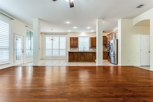 unfurnished living room featuring visible vents, a ceiling fan, light wood-type flooring, a sink, and recessed lighting