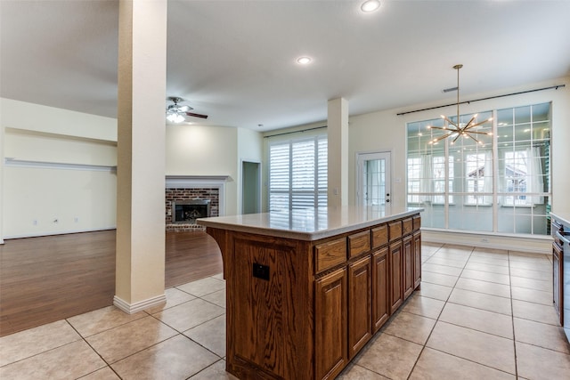 kitchen featuring light tile patterned floors, open floor plan, a center island, light countertops, and a fireplace