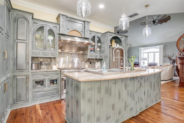 kitchen with tasteful backsplash, visible vents, ventilation hood, light wood-style floors, and gas stove