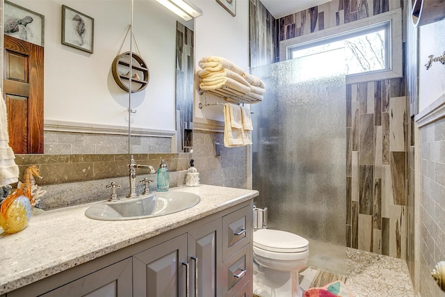 full bath featuring toilet, walk in shower, tile walls, and vanity