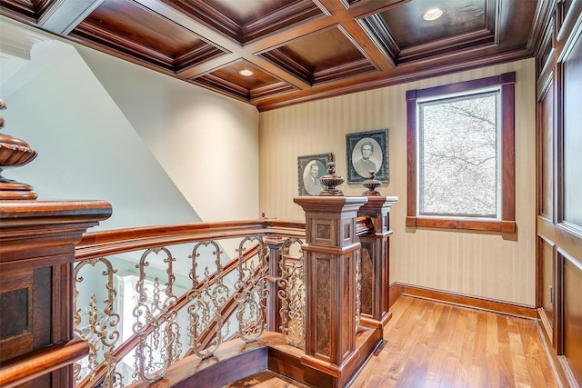 hallway featuring coffered ceiling, beamed ceiling, crown molding, an upstairs landing, and light wood-style floors