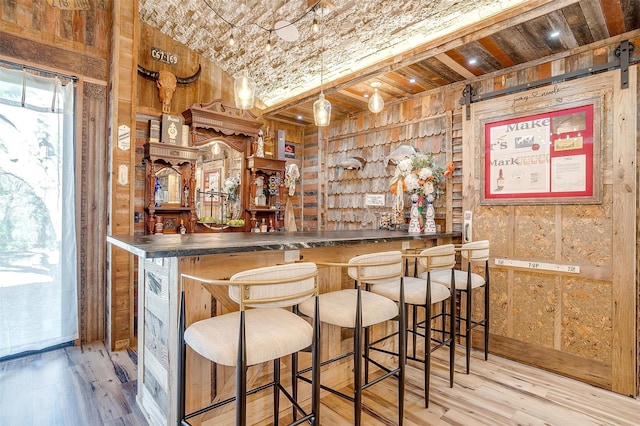 bar with a bar, brick ceiling, wooden walls, and wood finished floors