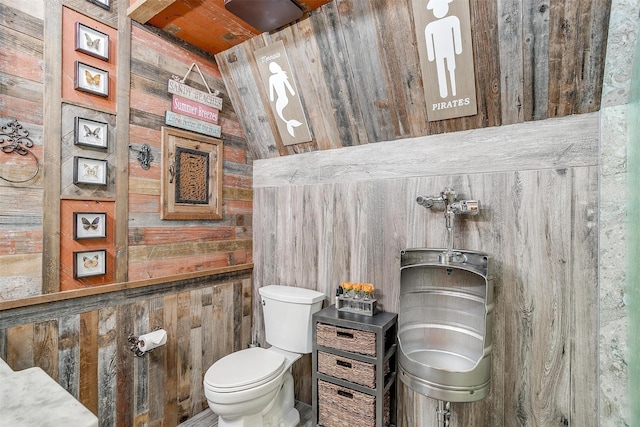 half bath with wood walls and toilet