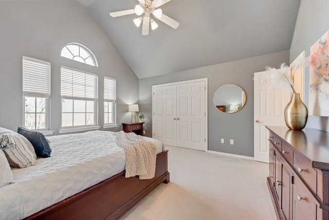 bedroom with high vaulted ceiling, light carpet, a ceiling fan, baseboards, and a closet