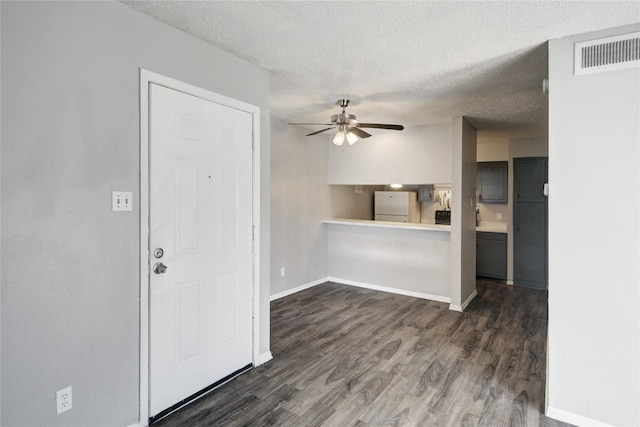 interior space featuring visible vents, baseboards, a ceiling fan, freestanding refrigerator, and dark wood-style floors