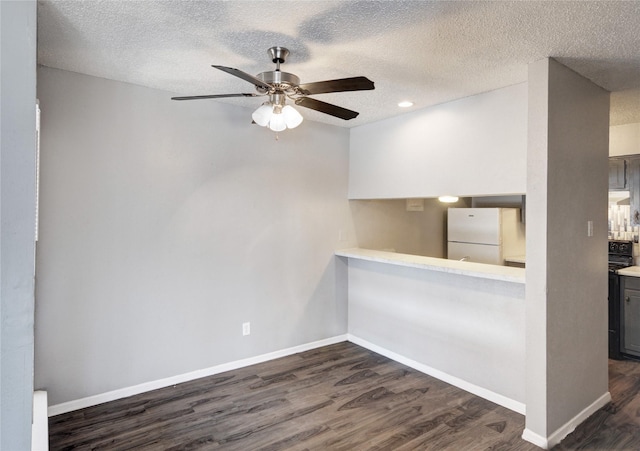 unfurnished room featuring ceiling fan, a textured ceiling, baseboards, and dark wood-type flooring