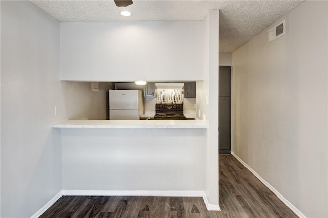 kitchen with light countertops, visible vents, dark wood-type flooring, freestanding refrigerator, and black range