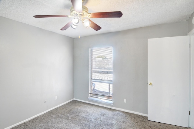 spare room with a textured ceiling, carpet floors, a ceiling fan, and baseboards