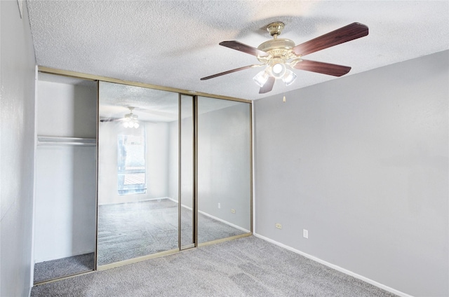 unfurnished bedroom featuring a textured ceiling, a ceiling fan, baseboards, a closet, and carpet