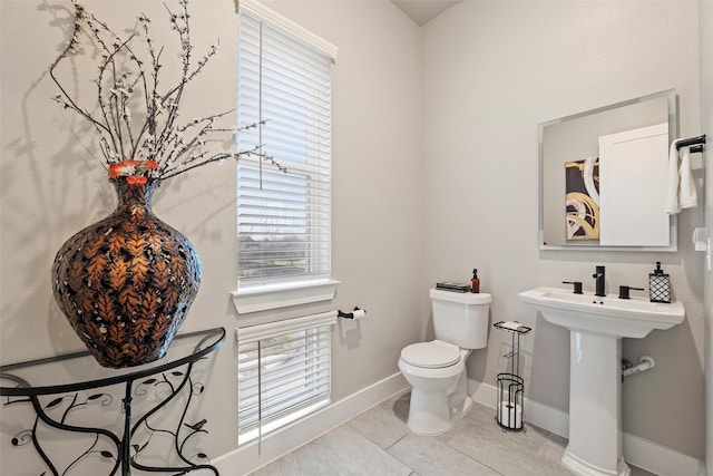 half bathroom with toilet, tile patterned flooring, and baseboards