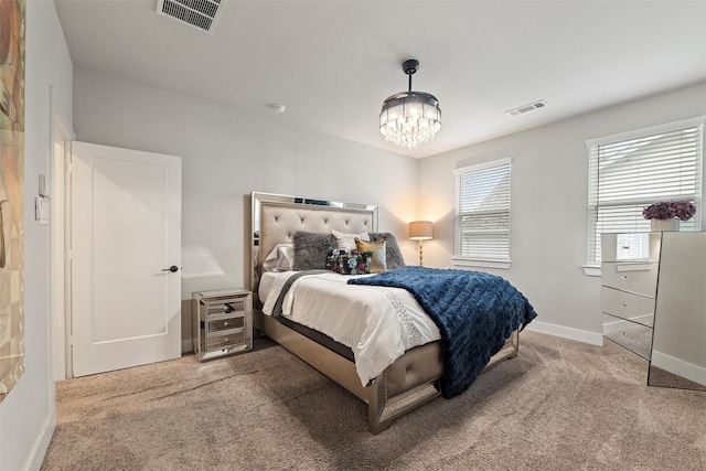 carpeted bedroom with baseboards, visible vents, and a chandelier