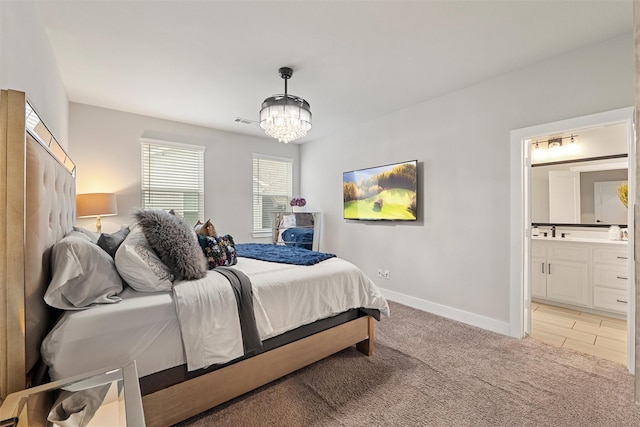 bedroom with a notable chandelier, light colored carpet, visible vents, baseboards, and ensuite bath