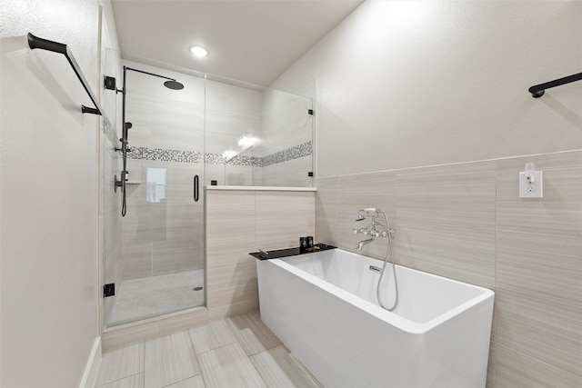 bathroom featuring a freestanding tub, tile walls, and a shower stall