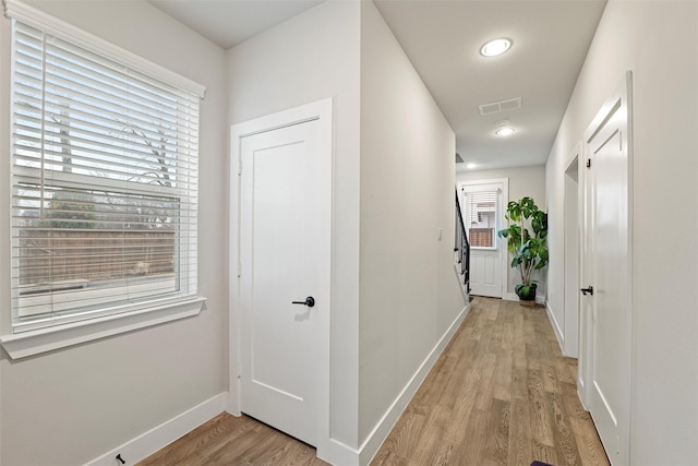 hallway featuring light wood-style flooring, visible vents, and baseboards