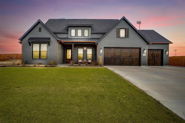 modern farmhouse with metal roof, a shingled roof, concrete driveway, a standing seam roof, and a front yard