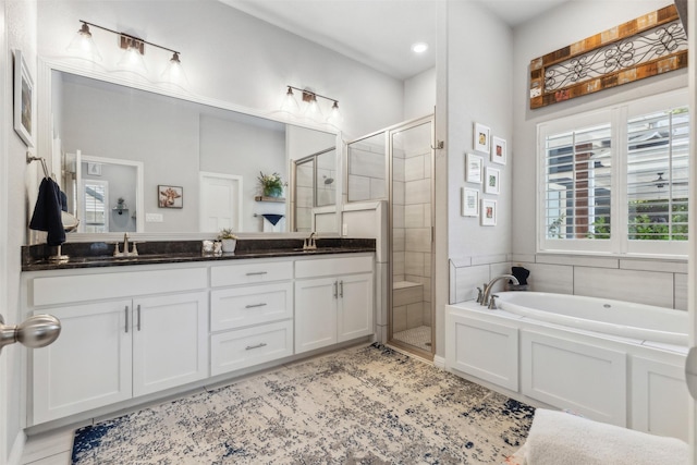 full bathroom featuring double vanity, a stall shower, a sink, and a bath