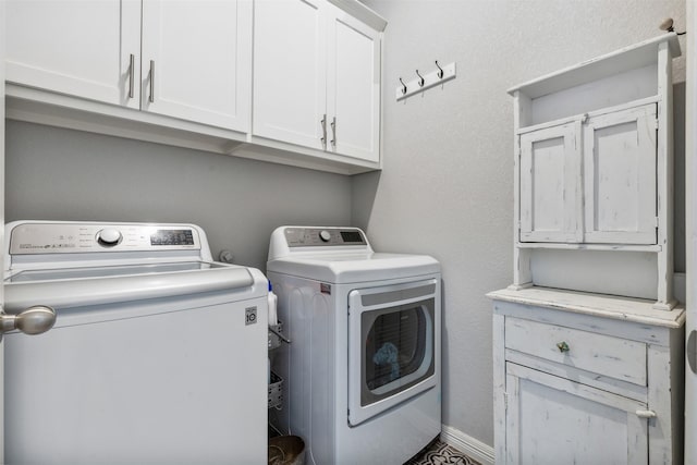 clothes washing area featuring cabinet space, baseboards, and separate washer and dryer