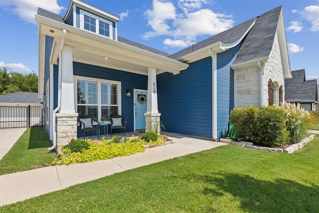 view of front of house featuring stone siding, a front lawn, and a porch