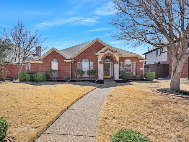 view of front of home featuring a chimney, fence, a front lawn, and brick siding