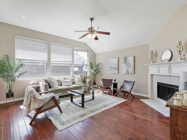 living room with ceiling fan, lofted ceiling, wood-type flooring, baseboards, and a tiled fireplace