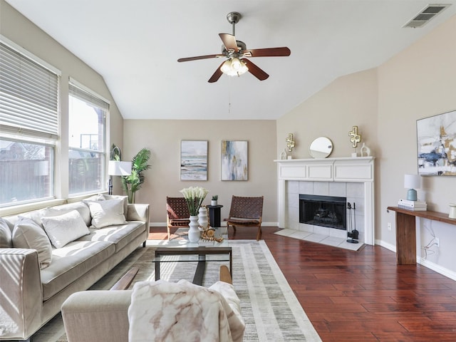 living area featuring baseboards, visible vents, lofted ceiling, wood finished floors, and a fireplace