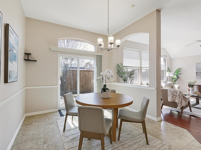 dining area with lofted ceiling, light tile patterned floors, baseboards, and a notable chandelier