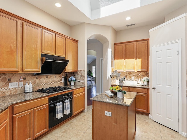 kitchen featuring visible vents, arched walkways, light stone countertops, extractor fan, and black appliances