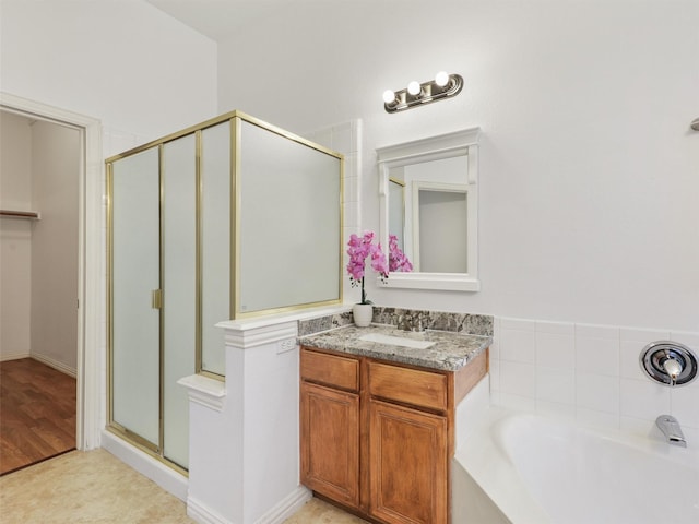 bathroom featuring a garden tub, a shower stall, and vanity