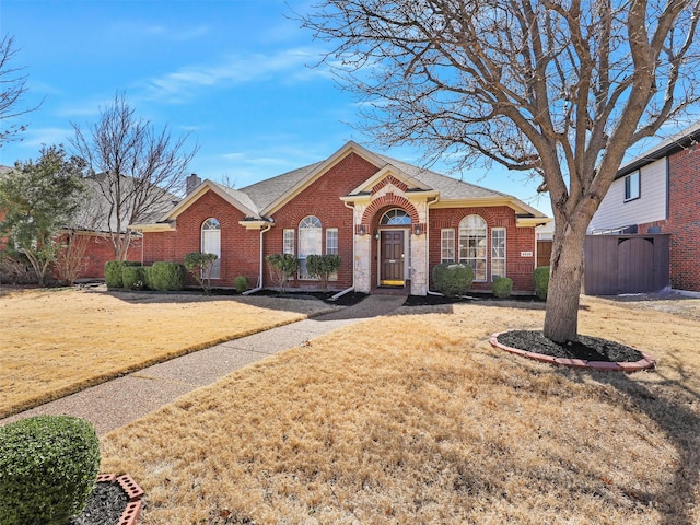 view of front of property featuring a front yard, a chimney, fence, and brick siding