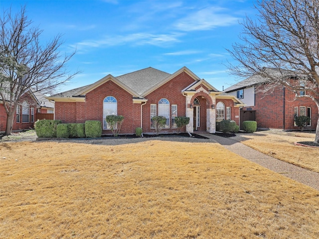 view of front of home featuring brick siding, a front lawn, and a shingled roof