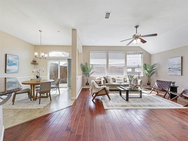 living area featuring baseboards, visible vents, lofted ceiling, dark wood-style floors, and ceiling fan with notable chandelier