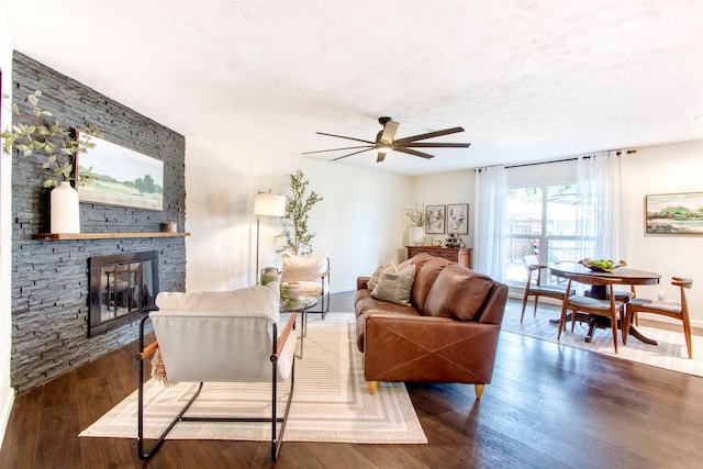 living area featuring a fireplace, a textured ceiling, baseboards, and wood finished floors