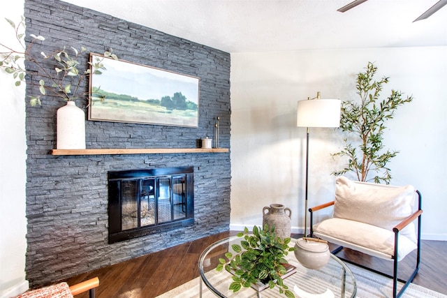 sitting room featuring a stone fireplace, wood finished floors, and baseboards