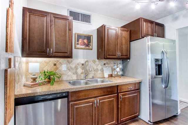 kitchen with visible vents, appliances with stainless steel finishes, wood finished floors, a sink, and backsplash