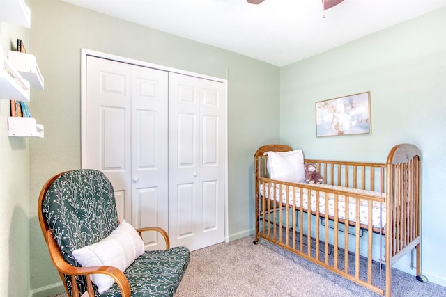 carpeted bedroom with a nursery area, baseboards, a ceiling fan, and a closet