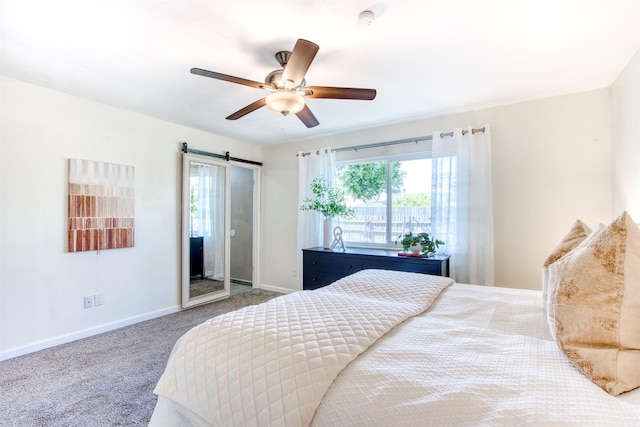 carpeted bedroom with a barn door, multiple windows, baseboards, and ceiling fan