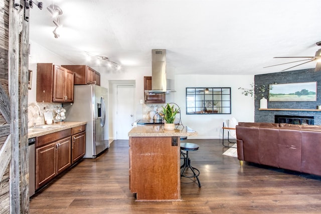 kitchen with island range hood, stainless steel fridge with ice dispenser, open floor plan, a fireplace, and a sink