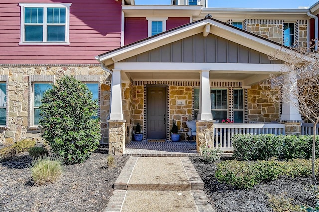 entrance to property with stone siding, covered porch, and board and batten siding