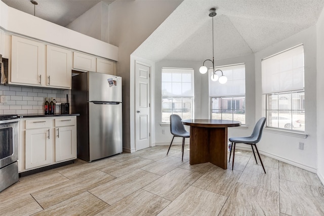 kitchen featuring appliances with stainless steel finishes, dark countertops, lofted ceiling, and decorative backsplash