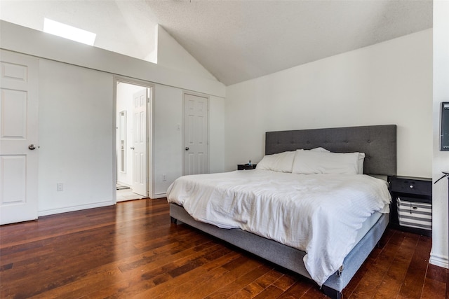 bedroom with lofted ceiling, wood-type flooring, ensuite bath, and baseboards