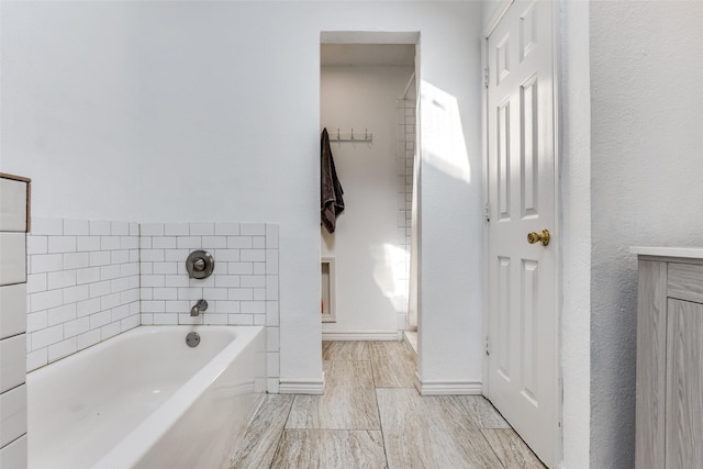 bathroom featuring wood finish floors, a garden tub, and baseboards