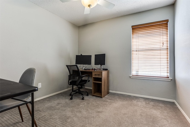 carpeted office space featuring a textured ceiling, a ceiling fan, and baseboards