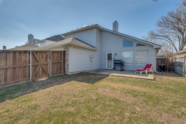 rear view of property with a yard, a fenced backyard, a patio, and a chimney