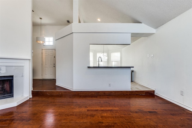 unfurnished living room with visible vents, an inviting chandelier, a high end fireplace, a textured ceiling, and wood finished floors