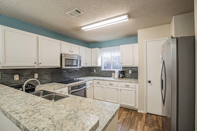 kitchen featuring stainless steel appliances, a peninsula, a sink, visible vents, and light countertops