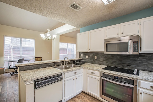 kitchen with visible vents, decorative backsplash, appliances with stainless steel finishes, a sink, and a peninsula